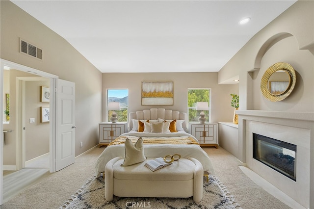 bedroom with light carpet, baseboards, a fireplace with flush hearth, and visible vents
