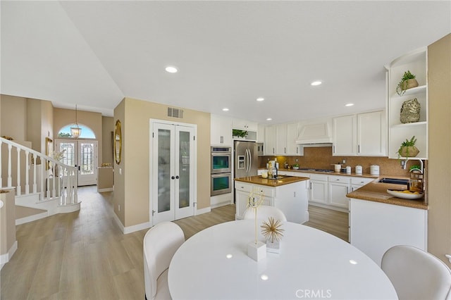 dining area featuring baseboards, light wood-style floors, french doors, and visible vents