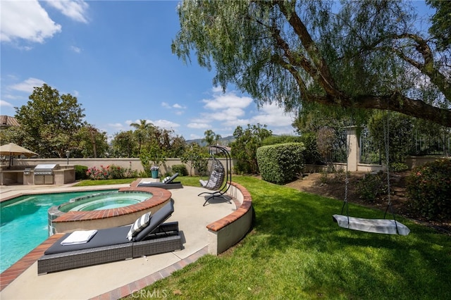 view of pool with a yard, a patio area, exterior kitchen, and a pool with connected hot tub