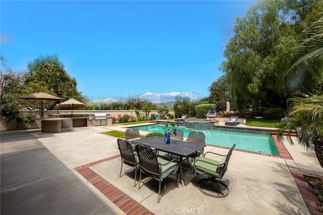 view of pool with a patio area, area for grilling, outdoor dining space, and a mountain view