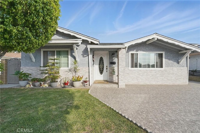 single story home featuring a front lawn, stucco siding, and a gate