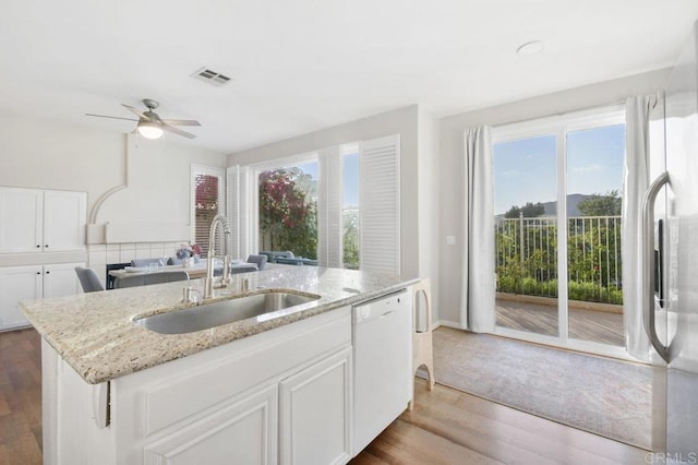 18562 Caminito Pasadero, San Diego, CA 92128 - kitchen with white dishwasher, visible vents, a sink, wood finished floors, and an island with sink