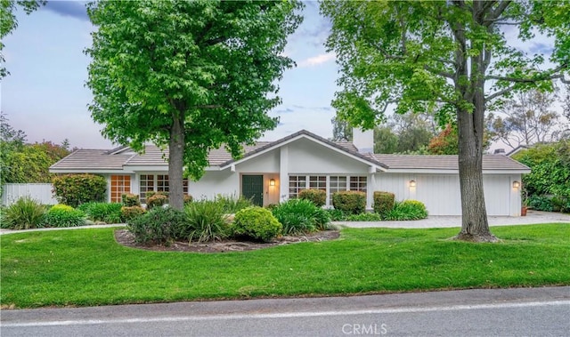 ranch-style house featuring a garage, a tile roof, and a front yard