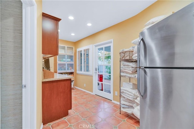 kitchen featuring freestanding refrigerator, light countertops, baseboards, and recessed lighting