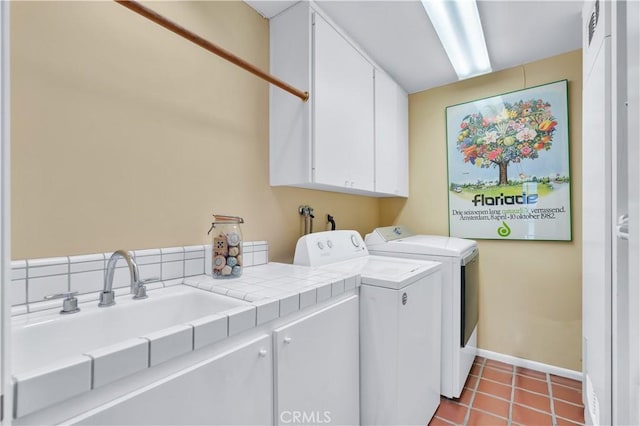 clothes washing area with a sink, cabinet space, tile patterned flooring, baseboards, and independent washer and dryer
