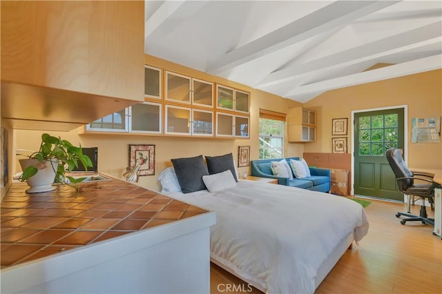 bedroom featuring light wood finished floors and lofted ceiling with beams