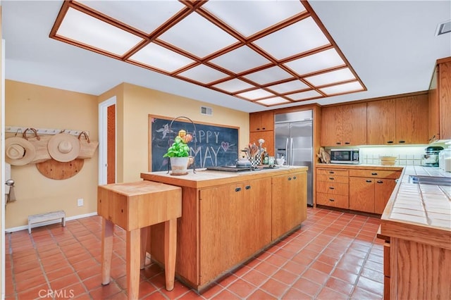 kitchen featuring light tile patterned floors, stainless steel appliances, baseboards, and tile counters