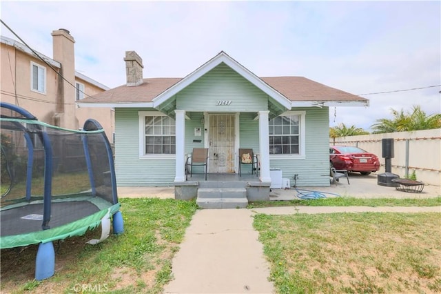 1341 N Fries, Wilmington, CA 90744 - bungalow-style home with covered porch, a trampoline, fence, and a front yard