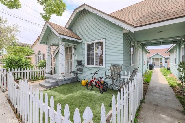 1341 N Fries, Wilmington, CA 90744 - view of front of house with a shingled roof, a front lawn, and a fenced backyard