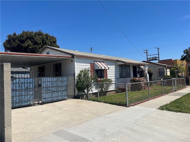 view of front of house with a fenced front yard, concrete driveway, a carport, and a gate