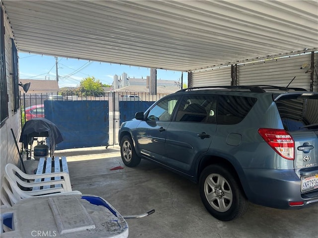 view of vehicle parking with fence and a carport
