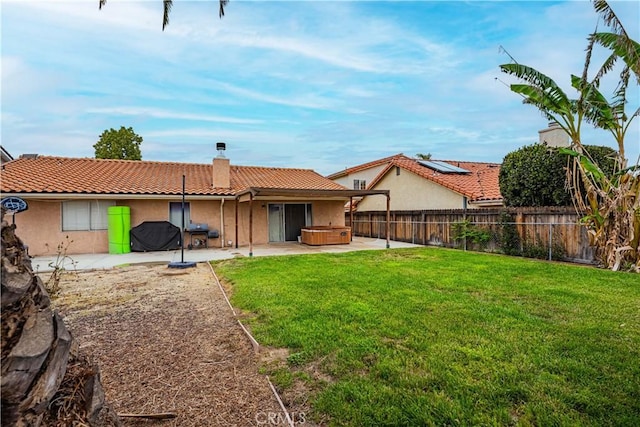 rear view of house featuring a tile roof, a chimney, a hot tub, a fenced backyard, and a patio area