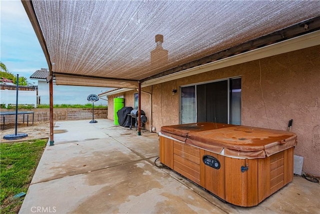 view of patio / terrace with a trampoline, a hot tub, and a fenced backyard