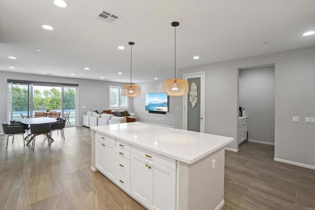 kitchen featuring white cabinets, a kitchen island, open floor plan, and recessed lighting