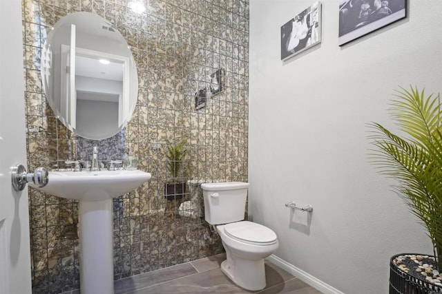 bathroom featuring toilet and tile walls