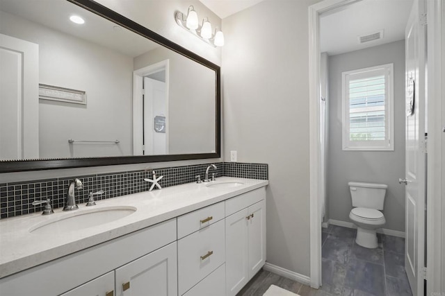 full bath featuring toilet, visible vents, tasteful backsplash, and a sink