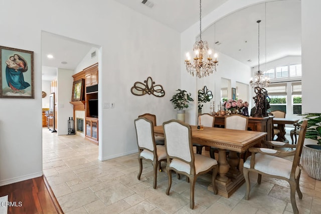 dining room featuring a notable chandelier, stone tile floors, baseboards, visible vents, and high vaulted ceiling