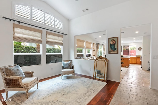 living area featuring recessed lighting, stone tile flooring, baseboards, visible vents, and high vaulted ceiling