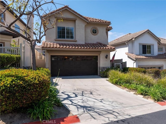 mediterranean / spanish-style house featuring stucco siding, concrete driveway, an attached garage, a tiled roof, and stone siding