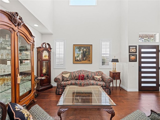 living room with a towering ceiling, baseboards, and hardwood / wood-style flooring