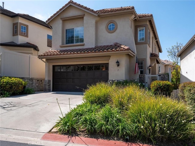 mediterranean / spanish home featuring a garage, fence, and a tiled roof