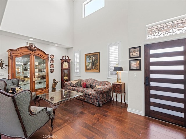 living room featuring wood finished floors, a high ceiling, and baseboards