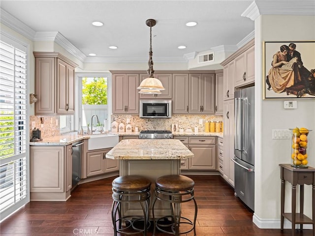 kitchen featuring appliances with stainless steel finishes, a center island, dark wood-style flooring, a sink, and decorative backsplash