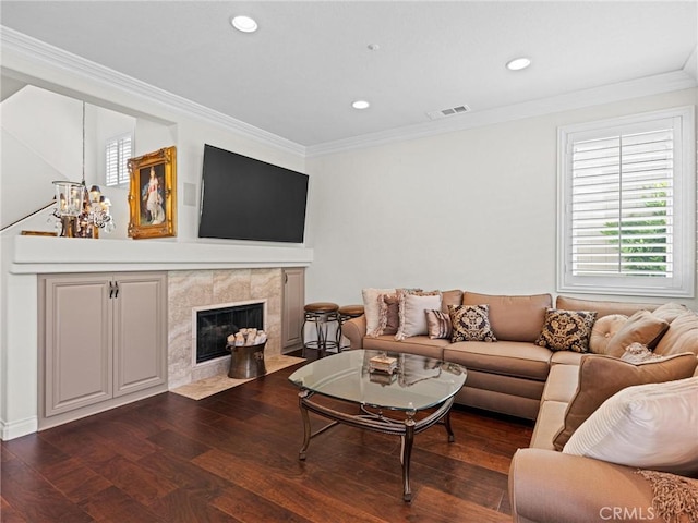 living room with plenty of natural light, crown molding, a tile fireplace, wood finished floors, and recessed lighting