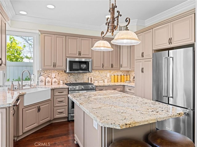 kitchen with high quality appliances, a sink, light stone countertops, a center island, and a kitchen bar