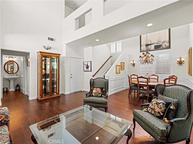 living room with wood finished floors, stairs, a chandelier, baseboards, and a towering ceiling