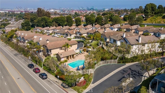 aerial view of property and surrounding area featuring a pool and nearby suburban area