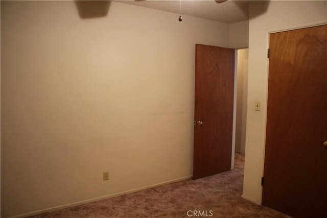 carpeted spare room with a ceiling fan, baseboards, and a textured ceiling