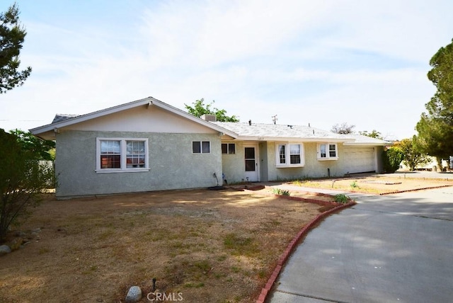 single story home with a garage, stucco siding, and driveway