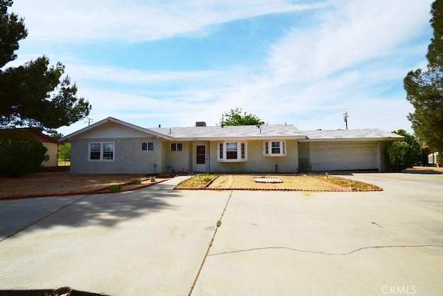 ranch-style house featuring concrete driveway, stucco siding, and an attached garage