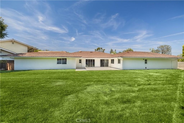 rear view of house with a yard, a patio area, and stucco siding