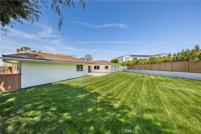 rear view of house featuring a fenced backyard, a patio, stucco siding, and a lawn
