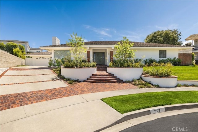 single story home featuring a garage, fence, a chimney, a front yard, and driveway