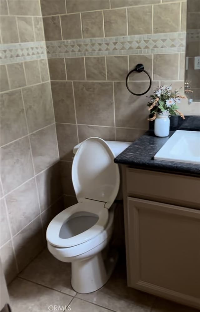 bathroom with tile walls, toilet, tile patterned flooring, and vanity