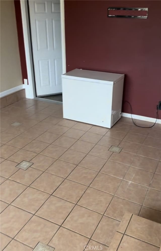 spare room with baseboards and light tile patterned floors
