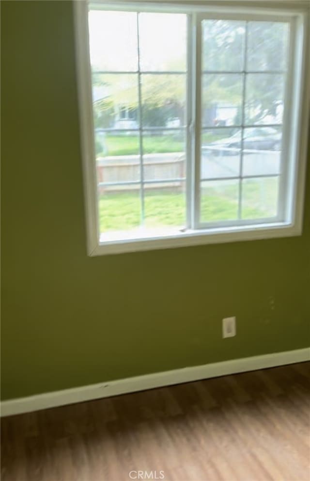 empty room featuring baseboards, dark wood-type flooring, and plenty of natural light