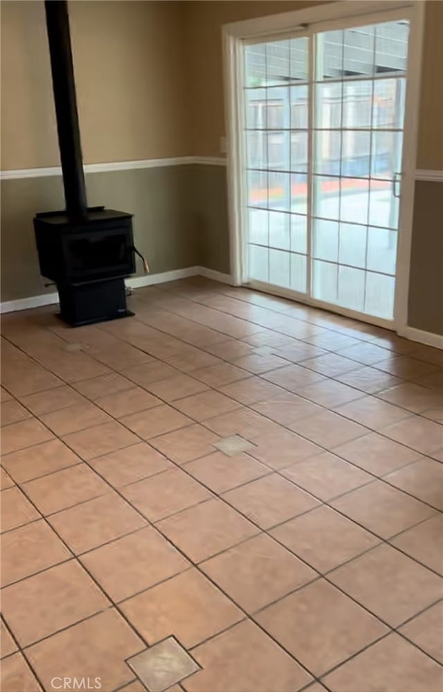 unfurnished living room featuring a wood stove and baseboards
