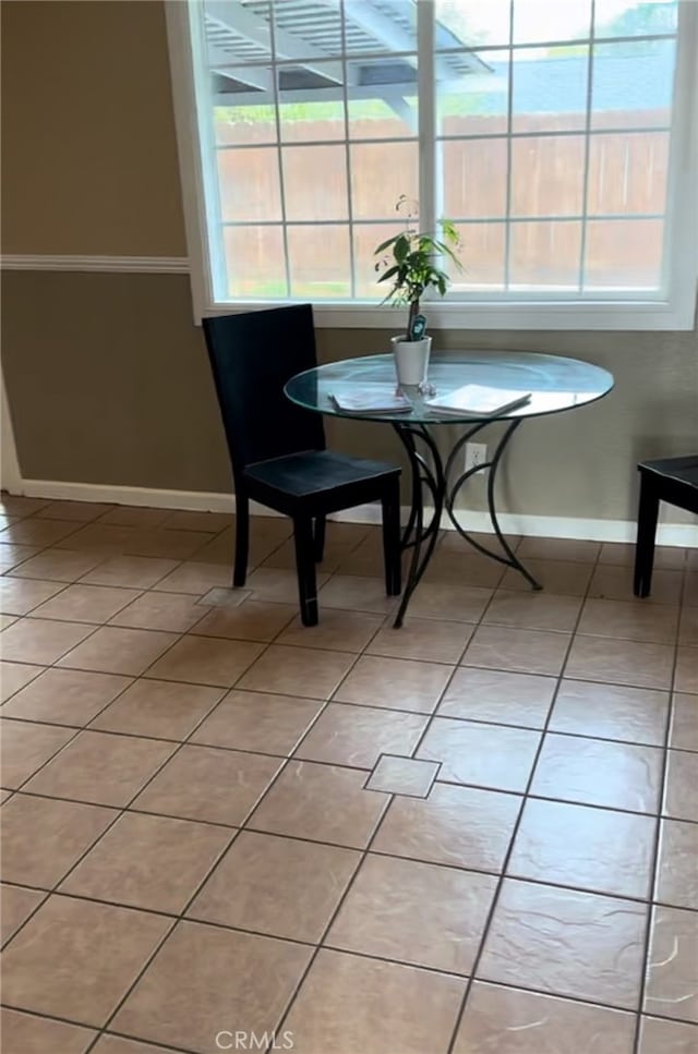 dining space with baseboards, a healthy amount of sunlight, and light tile patterned flooring