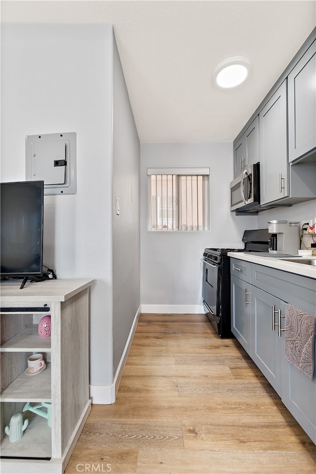 1301 E Pacific Coast, Wilmington, CA 90744 - kitchen featuring black gas stove, gray cabinetry, stainless steel microwave, light countertops, and baseboards