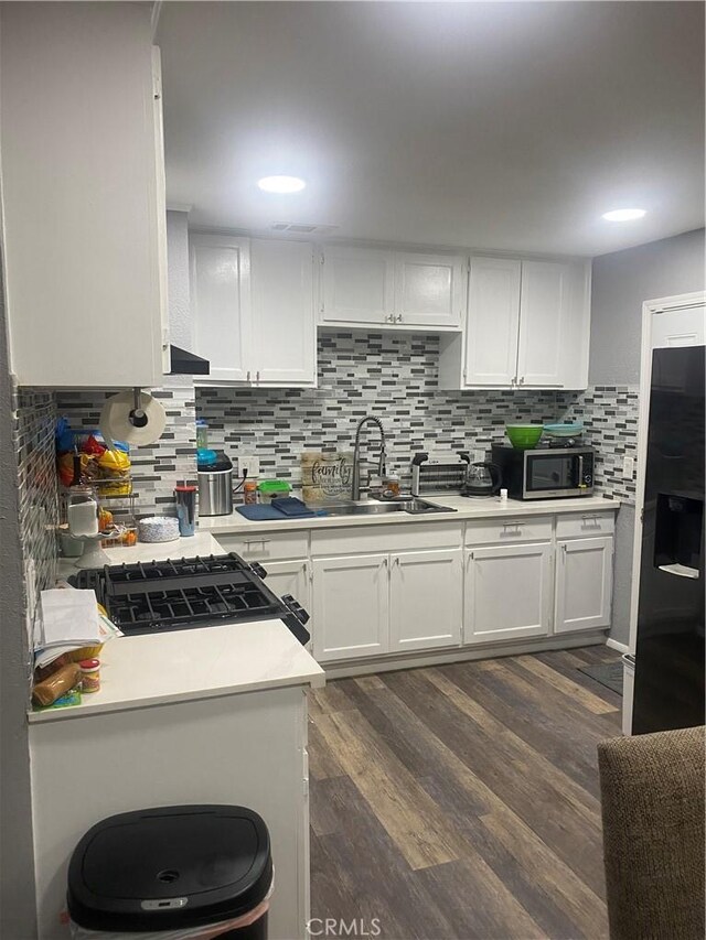 631 Chateau Way, Barstow, CA 92311 - kitchen with stainless steel microwave, a sink, black fridge with ice dispenser, white cabinetry, and light countertops