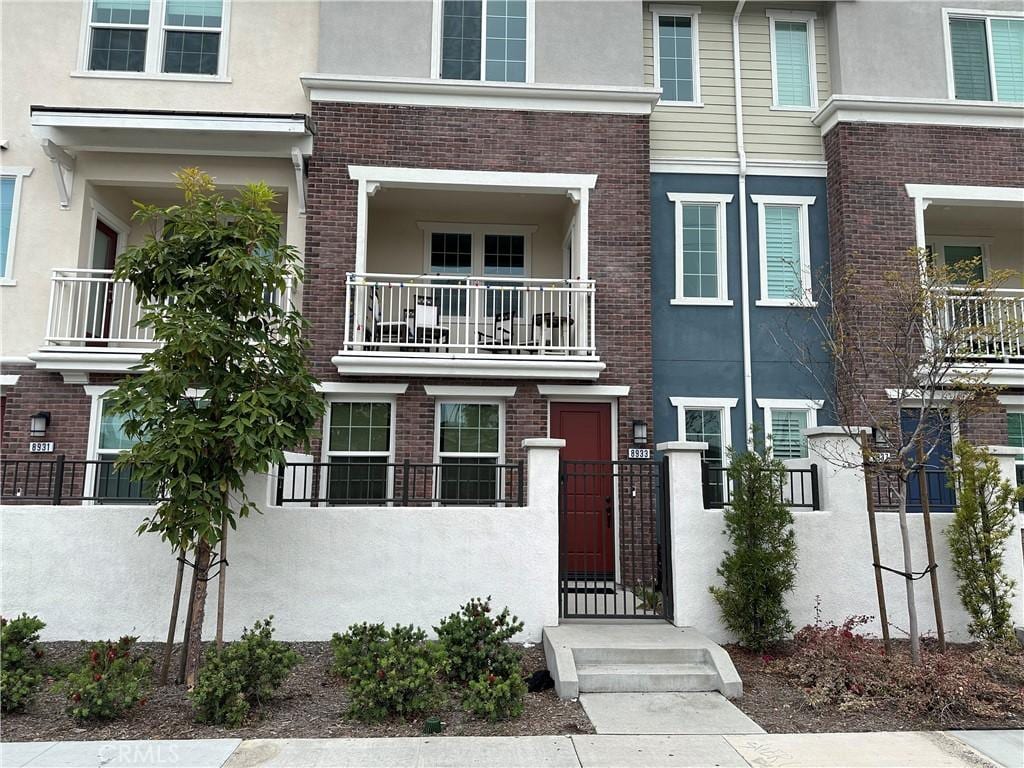 view of property featuring a fenced front yard, stucco siding, a gate, and brick siding
