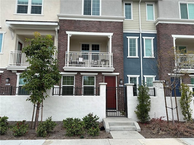 view of property featuring a fenced front yard, stucco siding, a gate, and brick siding