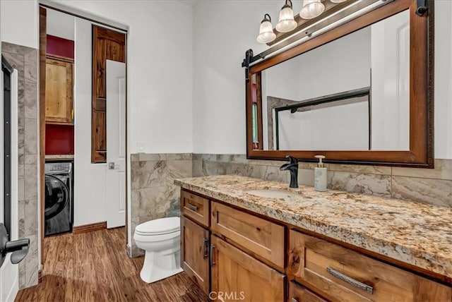 bathroom featuring washer / clothes dryer, tile walls, wood finished floors, vanity, and wainscoting