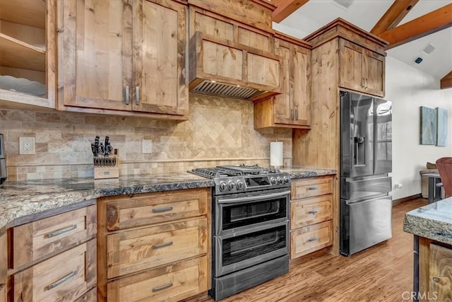 kitchen with light wood-style flooring, stainless steel appliances, dark stone counters, and vaulted ceiling with beams