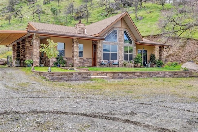 view of front of house with stone siding, stucco siding, and a chimney