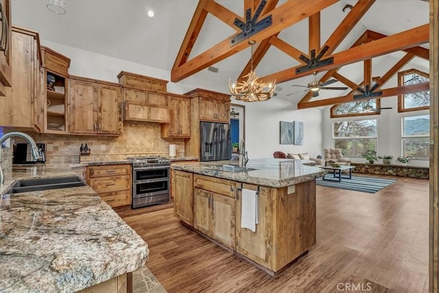 kitchen with ceiling fan with notable chandelier, appliances with stainless steel finishes, a sink, and high vaulted ceiling
